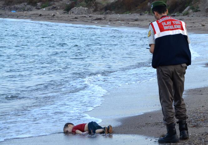Un policier turc observe le corps sans vie d'un petit garçon syrien rejeté par la mer à Bodrum après que le bateau où il se trouvait avec sa famille a coulé durant la tentative de traversée vers la Grèce, le 2 septembre 2015.