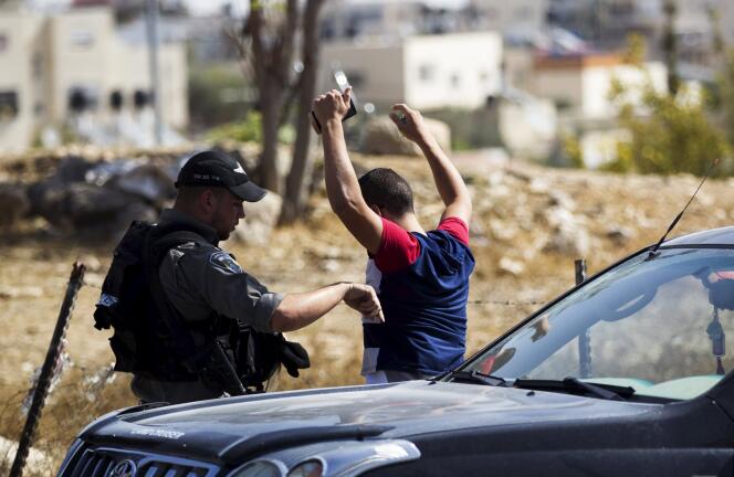 Un policier israélien contrôle un Palestinien à un barrage dans une zone de la Cisjordanie, le 14 octobre.