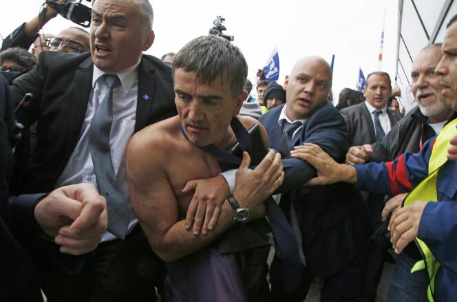 Le responsable des ressources humaines Xavier Broseta, torse nu, est évacué par des agents de sécurité lors du conseil d'entreprise d'Air France à Roissy le 5 octobre 2015.