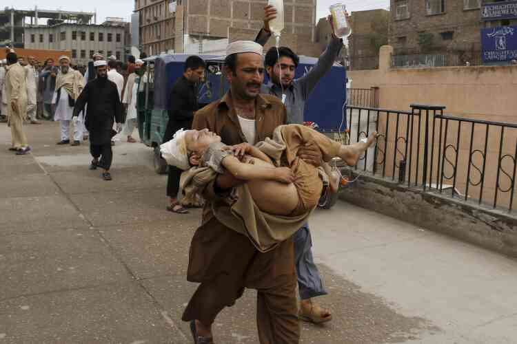 Un homme porte un jeune garçon blessé pendant le séisme, à Peshawar.
