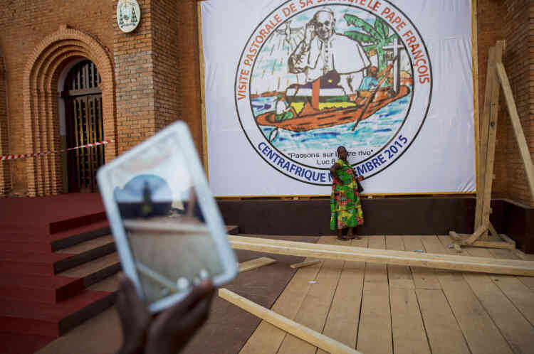 Bangui, le 28 novembre, des Centrafricains se photographient devant une banderole posée sur la façade de la Cathédrale à l'occasion de la venue du pape.