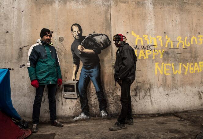 Deux migrants dans la jungle de Calais entourent, le 12 décembre, le graffiti de Banksy représentant Steve Jobs, fils d'un immigré syrien.