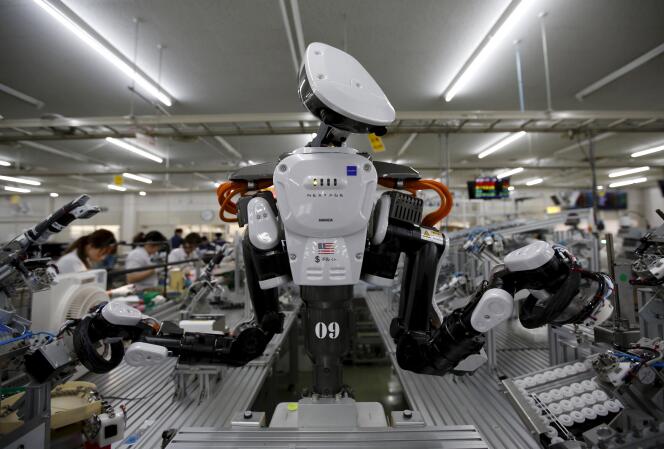 Un robot travaille à côté d'humains dans une usine de Kazo au Japon le 1 juillet 2015.