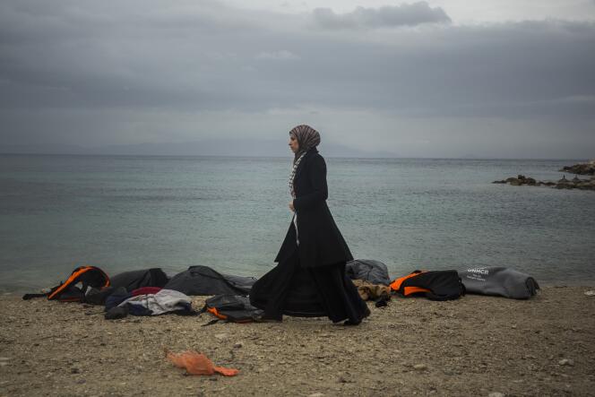 Une femme devant des gilets de sauvetage utilisés par des migrants pour se rendre en Europe, sur l'île grecque de Lesbos, le 5 janvier 2016.
