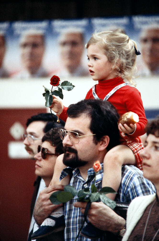Une fillette sur les épaules de son père, une rose à la main, écoute le discours du candidat socialiste à l'élection présidentielle François Mitterrand le 13 avril 1981 au cours du premier meeting de la campagne électorale.