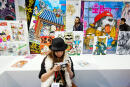 A woman looks at her camera as comics are displayed at the 39th edition of Angouleme world comic strip festival headed by American Art Spiegelman on the opening day, on January 27, 2012 in Angouleme, southwestern France. The 2012 festival is dedicated to Spain and is scheduled till January 29. Fifty-eight comics are in competition. AFP PHOTO/PIERRE DUFFOUR / AFP / PIERRE DUFFOUR