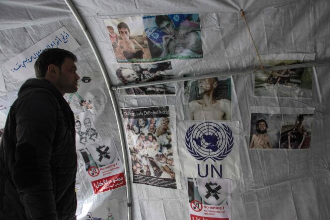 Un Syrien regarde des photos affichées dans une tente, à Alep, le 10 janvier, lors d'une manifestation en soutien aux habitants de Madaya.