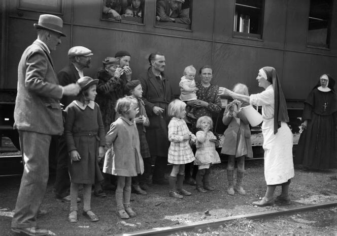 Une infirmière distribue de l'eau à des familles de réfugiés, dans une gare française, en mai 1940, durant la seconde guerre mondiale. / AFP