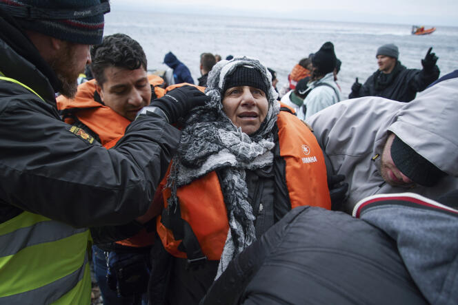 Des volontaires grecs viennent en aide à une femme qui vient de faire la traversée depuis la Turquie jusqu'à l'île grecque de Lesbos, le 26 janvier.