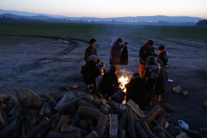 Des réfugiés se réchauffent autour d'un feu près du village frontière d'Idomeni en Grèce le 21 janvier 2016.