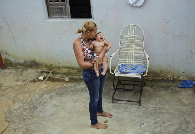 Gleyse Kelly, chez elle dans la favela d'Ibura, au Brésil. La jeune mère tient dans ses bras Maria Giovanni, sa plus jeune fille, atteinte de microcéphalie aiguë.