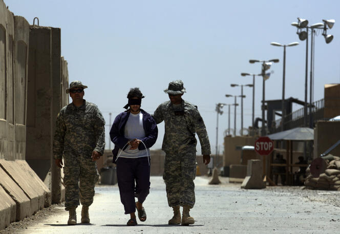 Des soldats américains escortent un détenu irakien dans le camp de détention de Cropper à Bagdad en 2008.