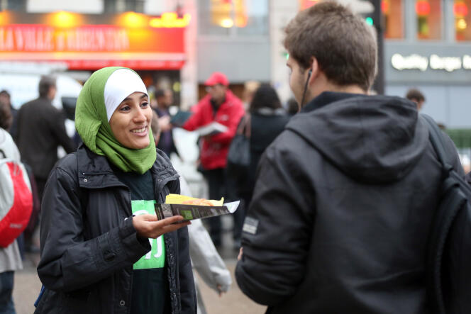 Une membre du Collectif contre l'islamophobie en France (CCIF) distribue des pains au chocolat en face de la gare Saint- Lazare, à Paris, en octobre 2012.