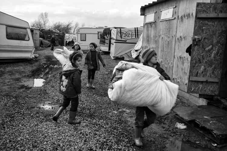 Des enfants déménagent des matelas et des couvertures, le 23 février, après l'annonce  d'une évacuation prochaine d’une partie du camp.