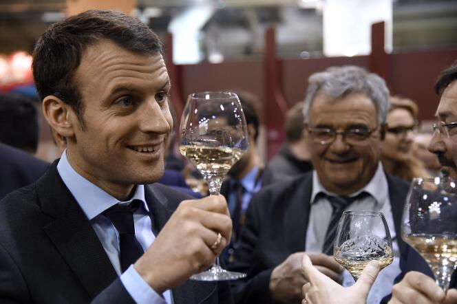 French Economy and Industry minister Emmanuel Macron tastes wine as he visits the Salon de l'Agriculture farm fair on March 3, 2016 in Paris. / AFP / DOMINIQUE FAGET
