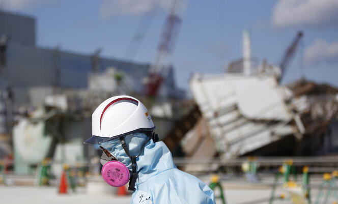 Un employé de Tepco marche devant le réacteur 1 de la centrale nucléaire de Fukushima, au Japon, en février 2016.