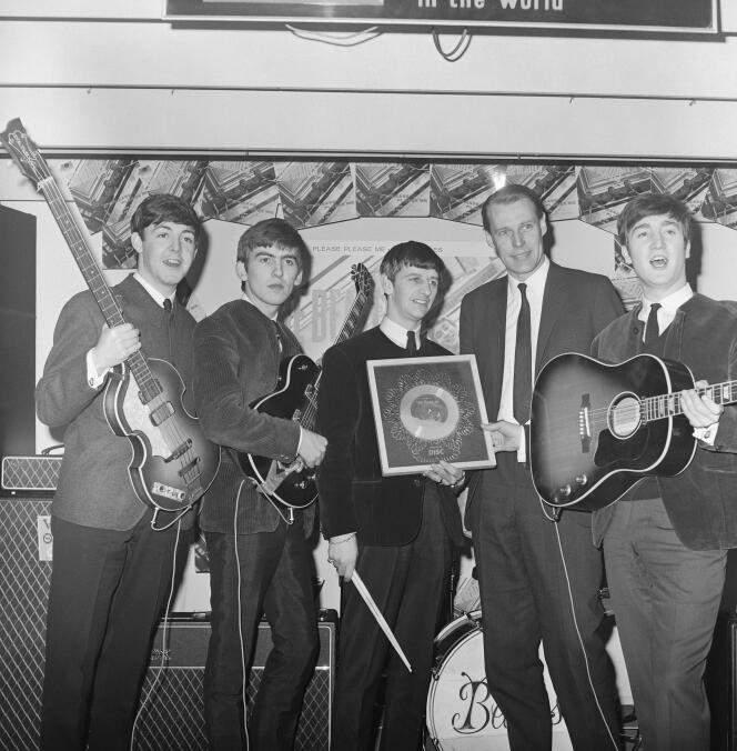 De gauche à droite, Paul McCartney, George Harrison, Ringo Starr, George Martin et John Lennon. A Londres, en 1964, lors de la remise d'un disque d'argent.