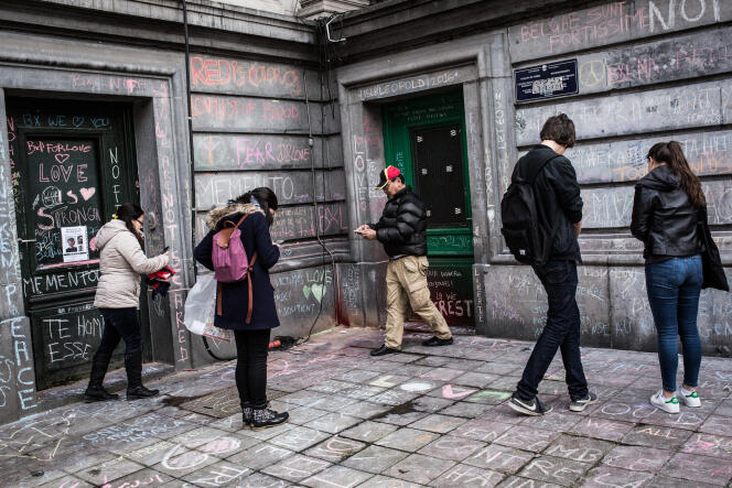 Des Bruxellois s’arrêtent pour photographier les messages de soutien  aux victimes qui recouvrent les murs dans le quartier  de la Bourse, devenu un lieu de recueillement.