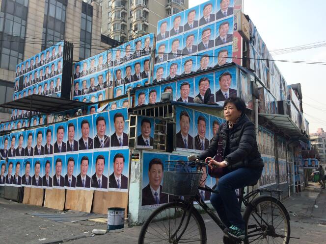 Une chinoise passe devant  une maison recouverte de posters du président  Xi Jinping à Shanghai le 26 Mars.