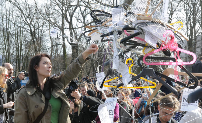 Une femme accroche un cintre, symbole de l’avortement clandestin, à un arbre devant le Parlement de Pologne.