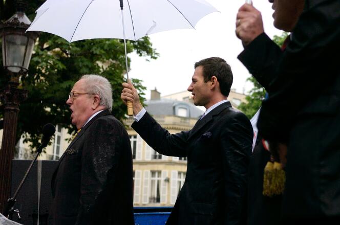 Jean-Marie Le Pen chante la Marseillaise, sous un parapluie tenu par Gérald Gérin,  à la fin d'un rassemblement du Front National devant l'Assemblée Nationale pour le rétablissement de la peine de mort pour les crimes les plus graves, à la suite des meurtres de deux enfants le 20 mai 2006