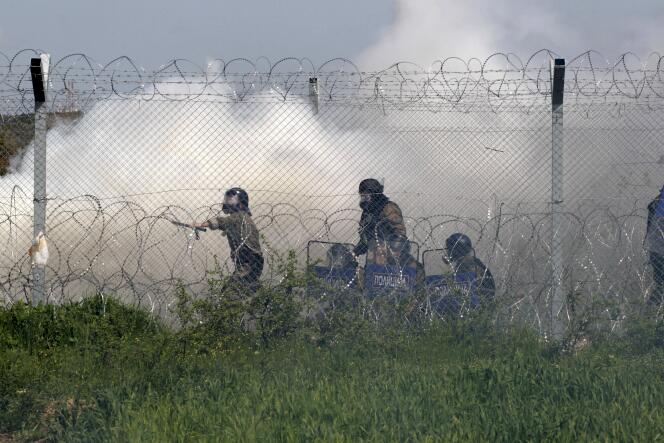 La police macédonienne, de l’autre côté du grillage marquant la frontière entre la Grèce et la Macédoine, lors des heurts avec les migrants, le 10 avril.