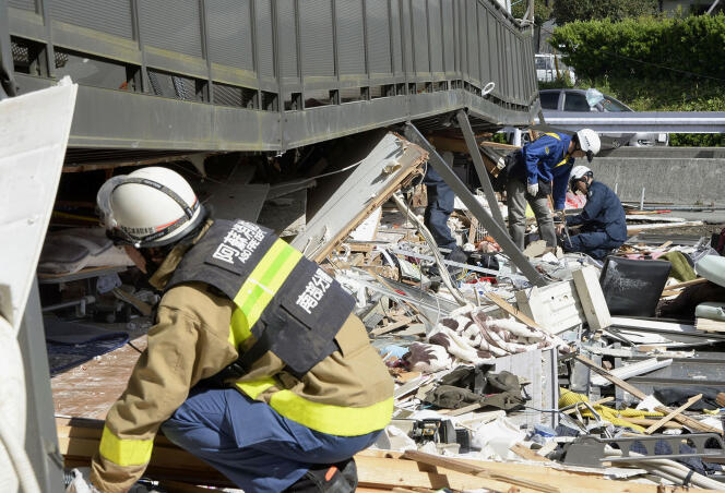 La police et les pompiers tentent d'extraire des personnes coincées dans les décombres d'un appartement dont le premier étage a été détruit par le séisme à Minamiaso, le 16 avril 2016.
