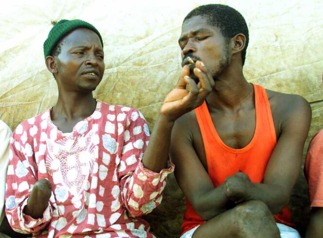 Dans un centre pour personnes amputées de Freetown, capitale de la Sierra Leone, deux amis partagent une cigarette, en mai 2000.