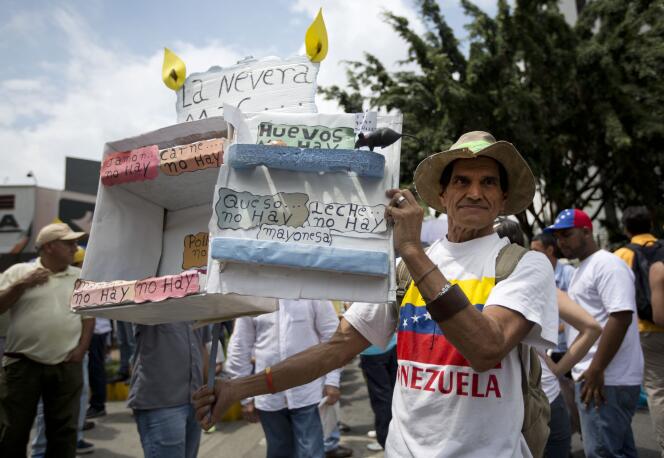 Un homme tient une boîte en carton représentant un frigo vide pour dénoncer la pénurie alimentaire qui frappe le Venezuela, lors d’un rassemblement de l’opposition, à Caracas, le 14 mai.