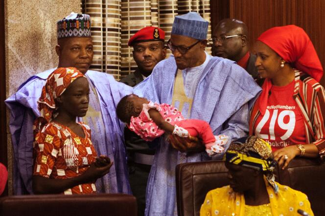 Le président nigérian Muhammadu Buhari tenant dans ses bras le bébé d’Amina Ali (en orange), première rescapée de Chibok retrouvée dans la forêt de Sambisa, le 19 mai.