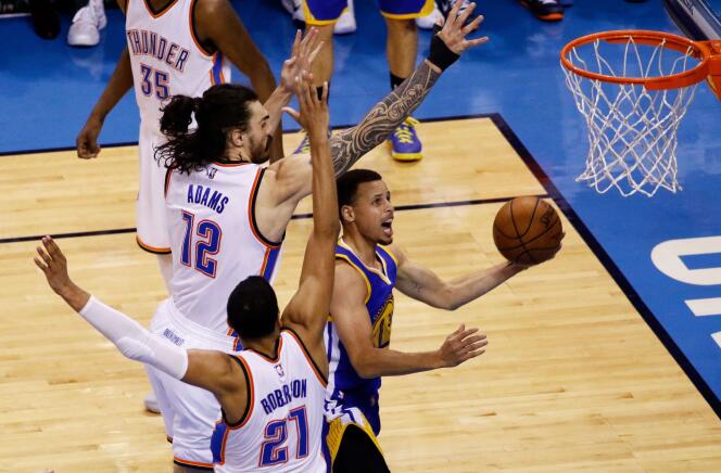 Stephen Curry (en bleu au centre) des Golden State Warriors au duel avec Steven Adams (en blanc, numéro 12) des Oklahoma City Thunder lors du troisième match de la finale de conférence Ouest.