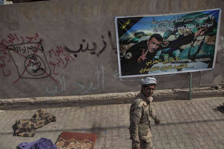 Les murs des quartiers libérés sont recouverts de noms de milices chiites des unités paragouvernementales de la mobilisation populaire (MP).Des inscriptions de la milice chiite Badr (en rouge) « 4e brigade. Badr » ont été tracées sur des inscriptions de l’EI (en noir) « Ya Zeinab », et les termes du drapeau : « Il n’y a d’autre dieu que Dieu et Mohammed est son prophète » sur un mur du quartier de Jolan. A droite,  une affiche représentant un journaliste de la communication de la Mobilisation populaire, mort en service, Fadhel Al-Garawiye.
