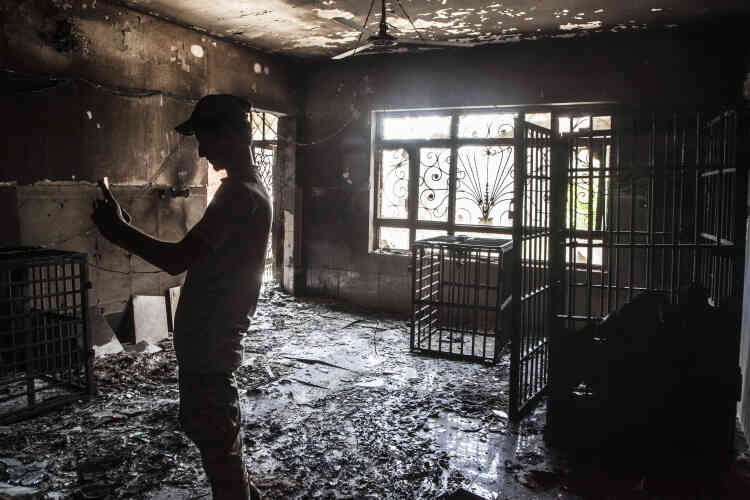 Un milicien chiite se photographie devant des cages de fer destinées à la détention dans une villa transformée en prison par l'organisation Etat islamique.