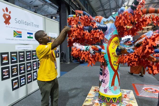 Un délégué accroche des rubans symboliques de la lutte contre le sida, à Durban (Afrique du Sud), le 19 juillet.