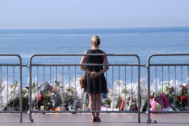 Une femme se receuille devant les fleurs déposées en hommage aux personnes tuées dans l’attentat de Nice, le 14 juillet.
