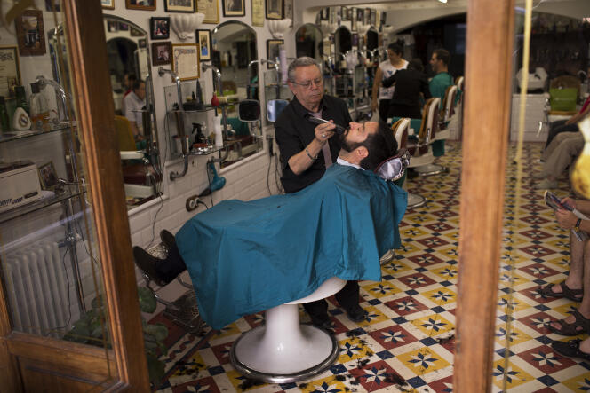 A barber trims the beard of a client in a barbershop in downtown Madrid, Spain, Friday, July 29, 2016. Spain's acting Prime Minister Mariano Rajoy was to begin calling opposition party leaders Friday in a bid to get badly needed parliamentary support after accepting the king's petition to try to form a government following last month's inconclusive elections. (AP Photo/Francisco Seco)