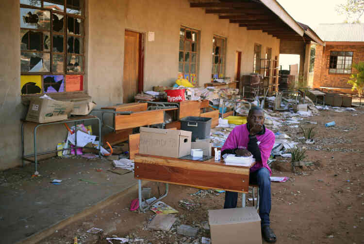 A Vuwani, un membre de la commission électorale indépendante patiente à l’extérieur d’une école endommagée par les émeutes de mai. L’école sert de bureau de vote pour les élections municipales.