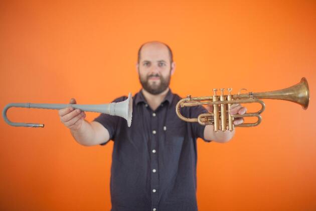 Jerôme Wiss présente, à gauche, une pièce imprimée en 3D qui a servi à prototyper la trompette finale, à droite.