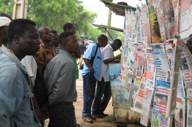 Des Togolais lisant les titres de presse, dans les rues de Lomé, au Togo.