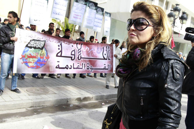 Une passante devant des partisans de Hizb Ut-Tahrir, lors d’une manifestation en face de l’amabassade de Franec à Tunis, le 14 février 2013.