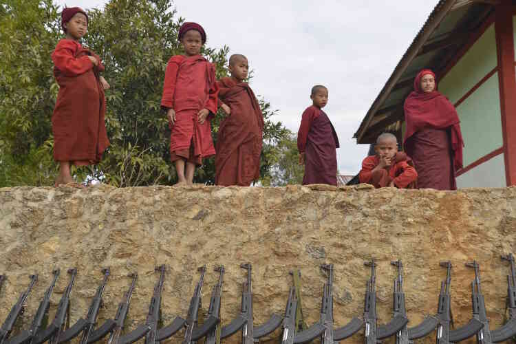 De jeunes novices bouddhistes regardent avec intérêt des soldats de la TNLA.