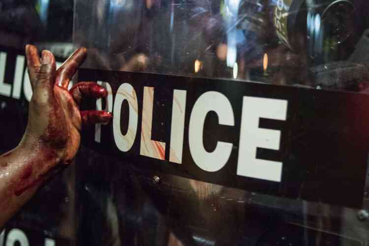 Une femme étale du sang sur le bouclier d’un policier.