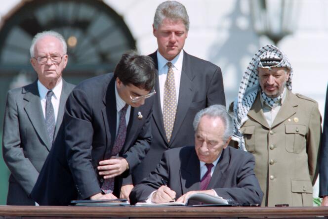 Shimon Pres paraphant les accords d’Oslo devant  Yitzak Rabin , le président américain Bill Clinton et celui de l’OLP Yasser Arafat à Washington le 13 septembre 1993.