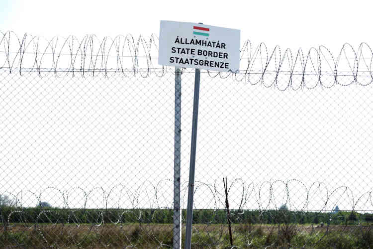 Un panneau sur la clôture annonce la frontière qui sépare la Hongrie de la Serbie.