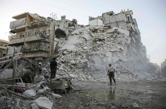 Des membres de la Défense civile syrienne, appelés les « casques blancs », à la recherche de victimes après la destruction d’un immeuble par un bombardement sur Alep, en octobre 2016.
