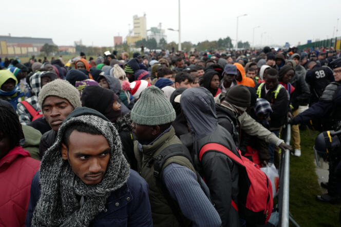 Des centaines de réfugiés attendent de monter dans l'un des bus qui les emmènera vers un centre d'accueil et d'orientation (CAO), le 24 octobre 2016 aux abords de la Jungle à Calais.
