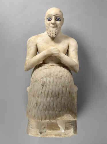 Retrouvée par André Parrot, en mission en Syrie (1933-1934), cette célèbre statue d’albâtre gisait, à Mari, la grande cité mésopotamienne, au sud du temple d’Ishtar, déesse de l’amour et de la guerre. Ses yeux, au regard vif donné par le lapis-lazuli souligné de noir comme du khôl, disent l’émerveillement et l’extase de l’adorant pour une « Ishtar virile », comme le dit l’inscription figurant sur son bras droit. Son titre « nu-banda » dit son appartenance aux élites du royaume. Elle date de 2350-2250 av.J.-C.