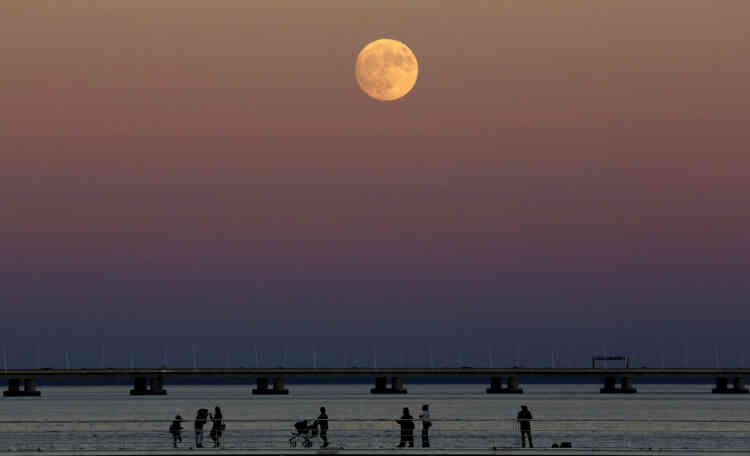 La Lune à son lever au-dessus du Tage à Lisbonne, au Portugal.