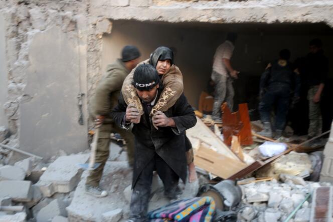 Un Syrien évacue une femme prise au piège d’un immeuble bombardé, à Alep, le 20 novembre.