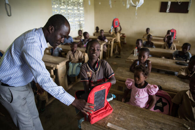 M. Nguettia, le directeur de l’école de Koroukro, vérifie les manuels présents dans le cartable solaire d’un élève.